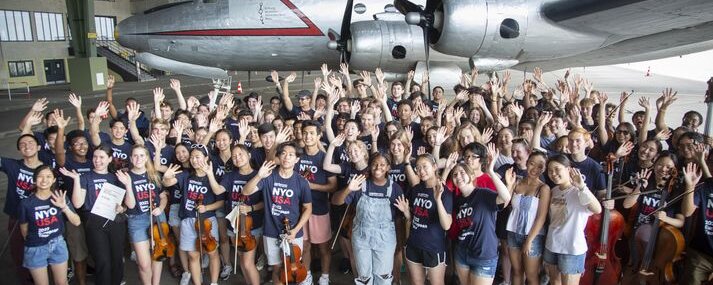 Jugendliche stehen mit ihren Musikinstrumenten vor dem Rosinenbomber 