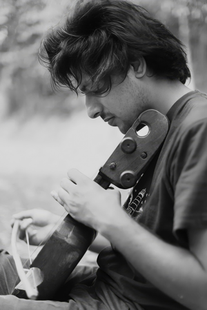 Schwarz-weiß Foto von Ranav Adhikari, der ein traditionelles, senkrecht gehaltenes Streichinstrument mit einem Bogen spielt. Der Fokus liegt auf den Händen und der detailreichen Struktur des Instruments, der Hintergrund ist weich verschwommen.