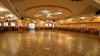 Festlicher Ballsaal der Tanzschule Traumtänzer am Flughafen Tempelhof, am Rand der Tanzfläche stehen Stühle und Tische.