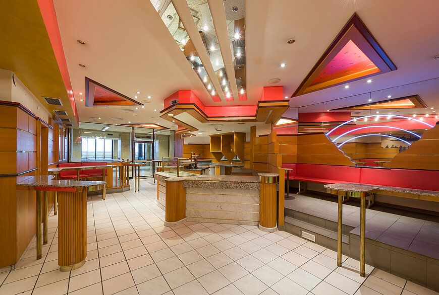Die Bar "Airlift" in der Haupthalle des Flughafen Tempelhof im Retro Stil, mit Barhockern, Fließen am Boden und Spiegelstreifen an der Decke 