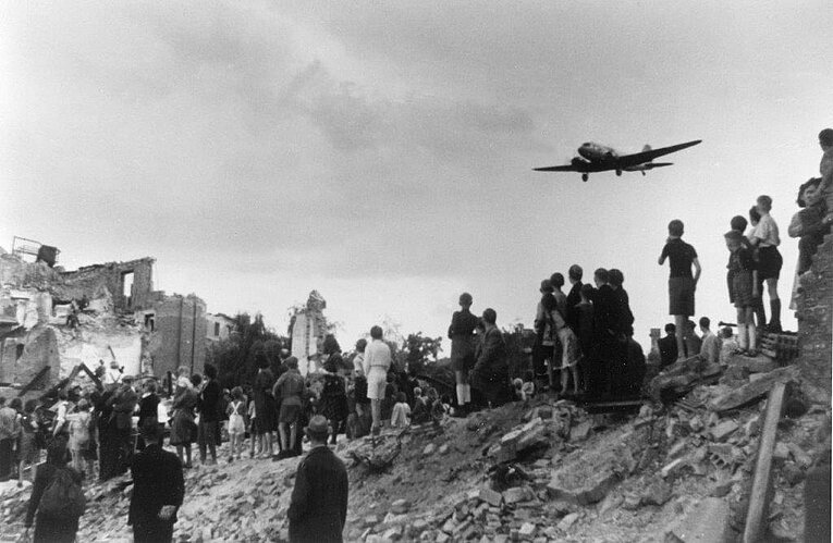 Blockade Berlin Bevölkerung beobachtet die Landung eines Luftbrueckenflugzeugs auf dem Flughafen, Aufnahme von 1948