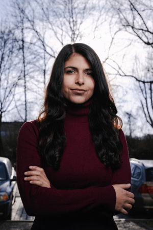 Daniela Sepehri steht draußen und hat die Arme vor dem Körper verschränkt.