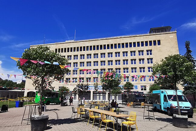 Blick auf die Außenfassade des THF TOWER. Auf der Außenfläche stehen Foodtrucks 
