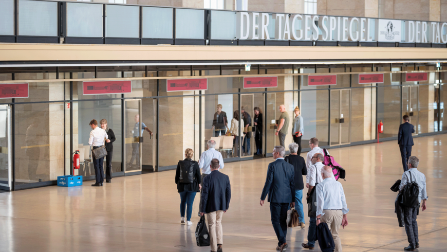 Menschen mit Business Kleidung laufen durch die Haupthalle des Flughafen Tempelhof