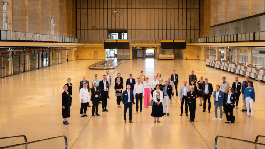 In der Haupthalle des Flughafen Tempelhof steht eine Menschengruppe 