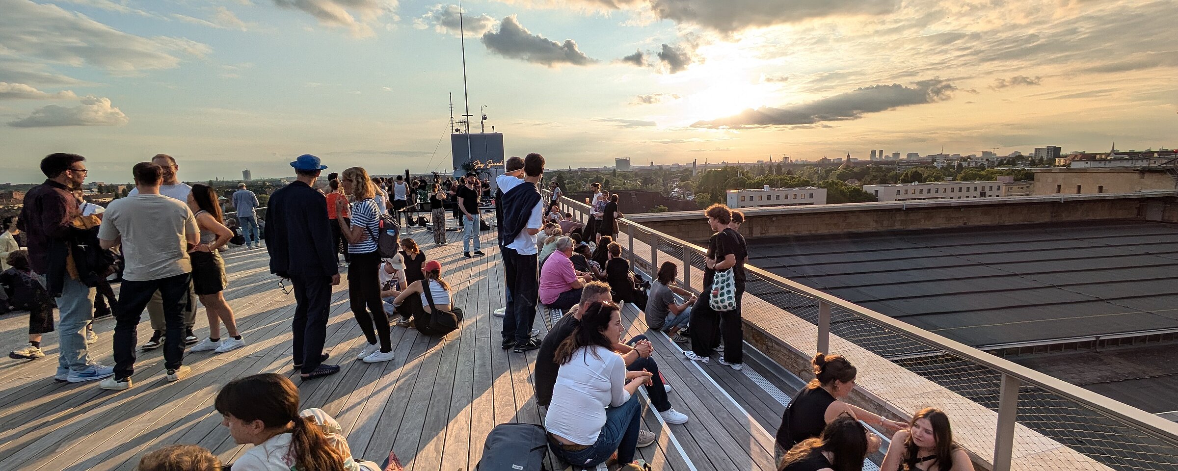 Viele Menschen sitzen auf der Dachterrasse des THF TOWER und lassen den abend ausklingen