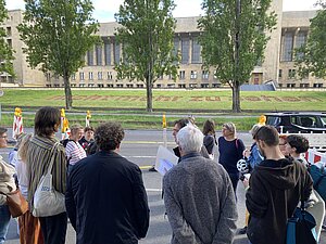 Eine Gruppe von Menschen steht vor dem Erinnerungszeichen "nicht mehr zu sehen".