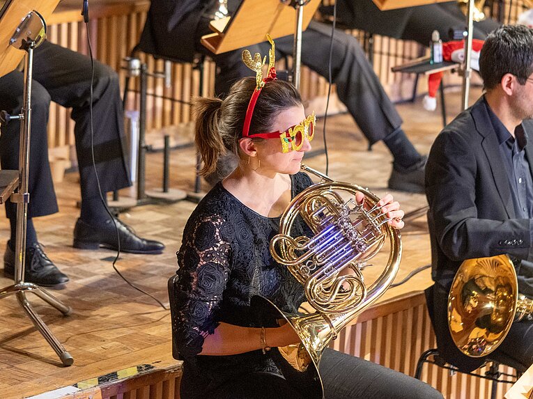 Weihnachten in Berlin: Musikerin mit weihnachtlichem Kostüm und Horn-Instrument