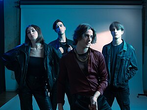 Die Bandmiglieder von Sector 5 posieren vor einer Studioleinwand, dabei steht einer der Musiker im Vordergrund.