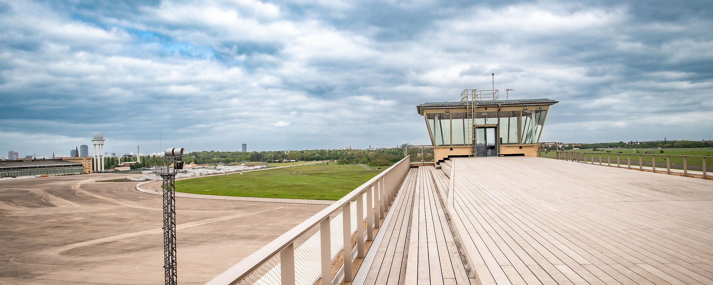 Die Dachterrasse des THF TOWERS mit Blick auf das Vorfeld des Flughafen Tempelhof und auf das Tempelhofer Feld. Blauer Himmel mit ein paar weißen Wolken