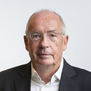 Joseph Hoppe in einem formellen Porträt: Er trägt eine Brille, ein weißes Hemd und ein dunkles Sakko und blickt ruhig in die Kamera vor hellem Hintergrund.