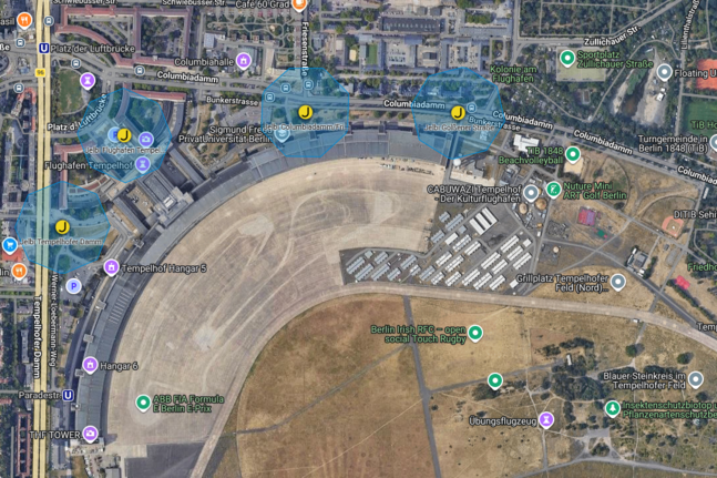 Satellitenkarte des Flughafen Tempelhof mit fünf markierten Standorten entlang des Columbiadamms, hervorgehoben durch blaue Umkreise und gelbe Symbole.