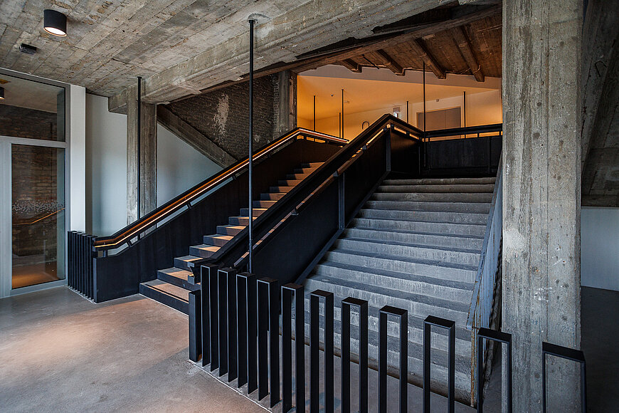 Rustikales Treppenhaus im THF TOWER mit schwarzen Metallgeländern