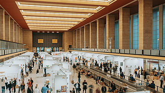 Viele Menschen in der Haupthalle des Flughafen Tempelhof, in der die Ausstellung Paper positions berlin stattfindet