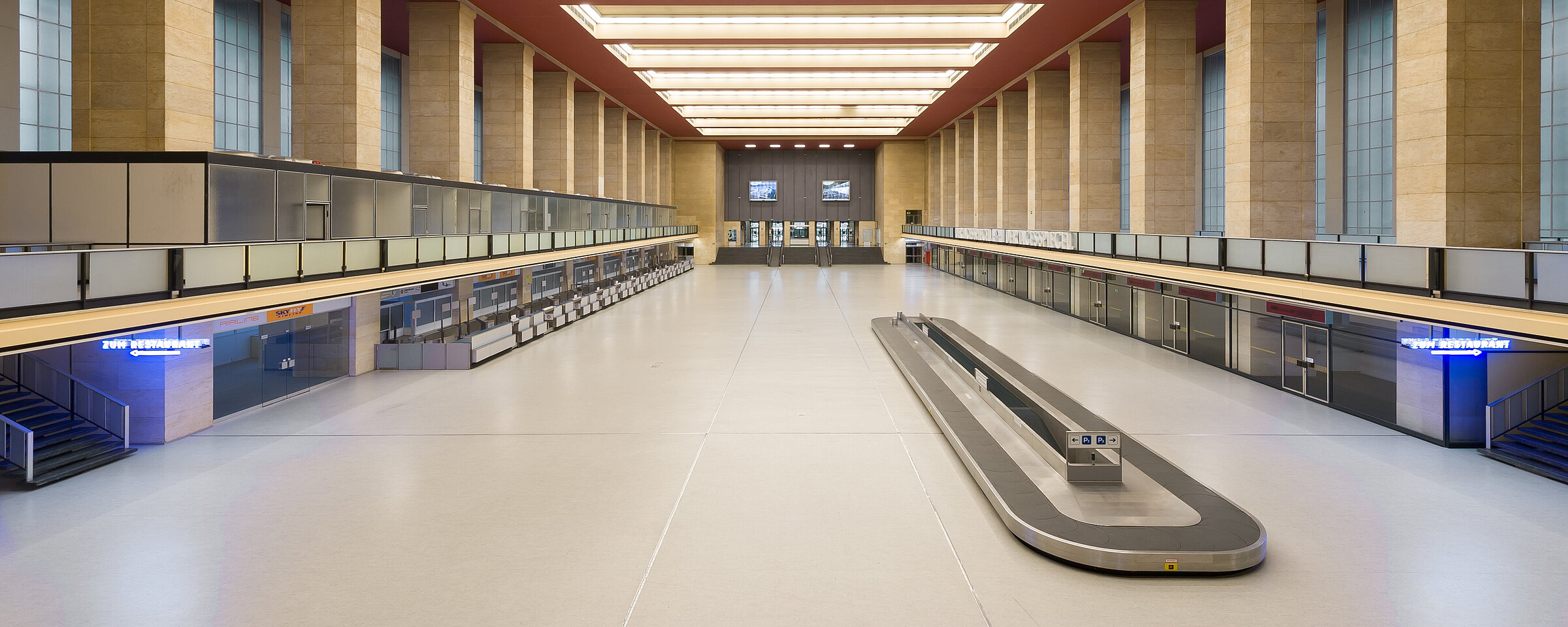 Blick in die leere Haupthalle am Flughafen Tempelhof, die vermietet werden kann. In der Mitte der riesigen Halle befindet sich das alte Gepäckband, an den Seiten die ehemaligen Flughafenschalter