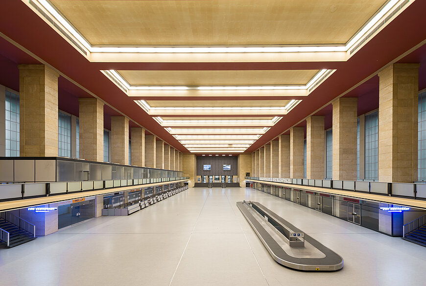 Blick in die leere Haupthalle am Flughafen Tempelhof, die vermietet werden kann. In der Mitte der riesigen Halle befindet sich das alte Gepäckband, an den Seiten die ehemaligen Flughafenschalter