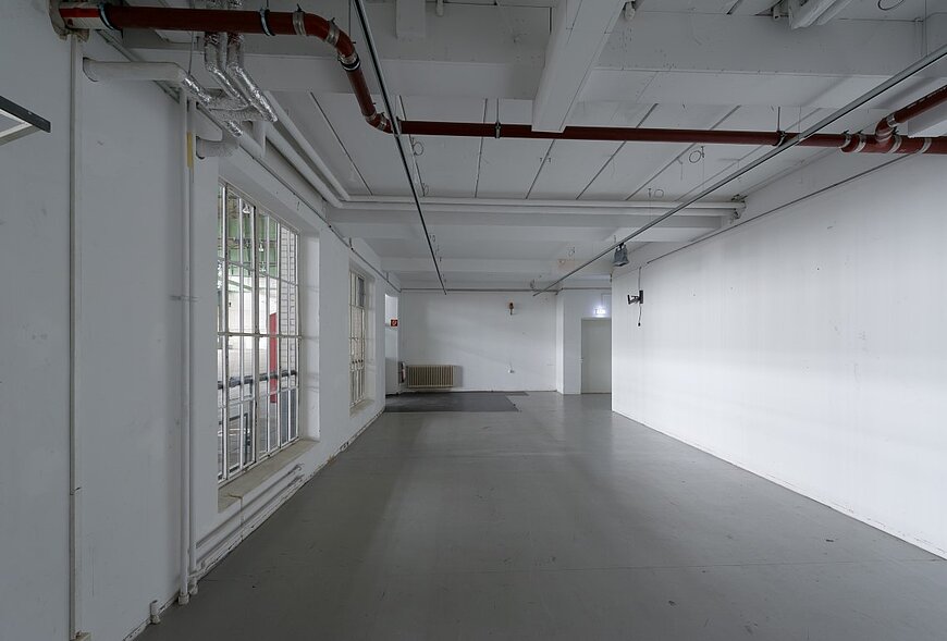 Innenansicht des Showrooms am Hangar 7. Helle, flexible Eventfläche mit hohen Decken, großen Fenstern und moderner Industrieästhetik für Seminare, Workshops oder Produktpräsentationen.