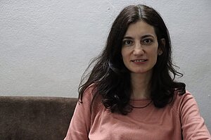 Porträt von Meral Çiçek, die vor einer weißen Wand sitzt