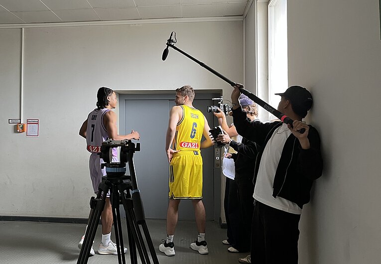 Werbefilmdreh vor einem Fahrstuhl im Flughafen Tempelhof. 2 Basketballspieler stehen vor der verschlossenen Fahrstuhltür ein Kameramann und ein Tonmann stehen vor ihnen