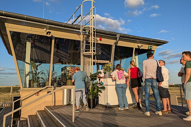 Ehemalige Fluglotsen Tower am Flughafen Tempelhof im Sommer. Menschen stehen in einer Schlange vor einer temporären Bar