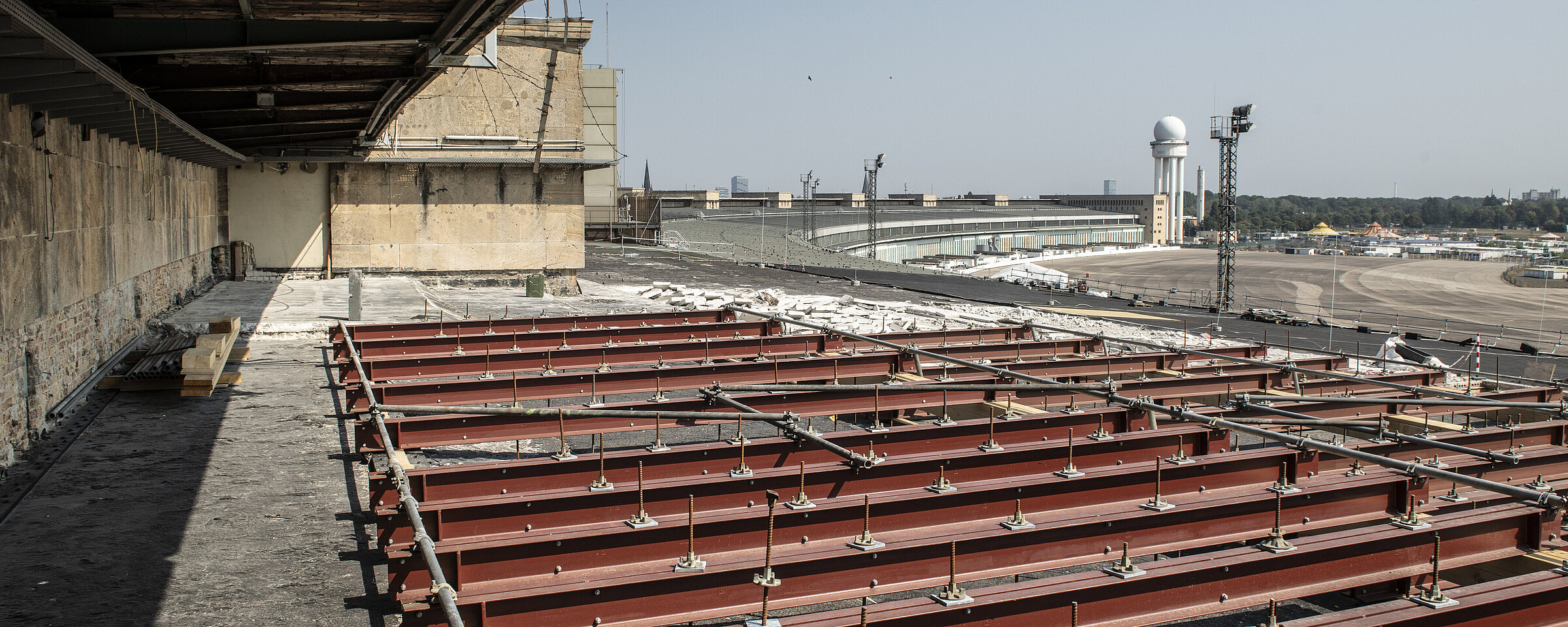 Blick auf die Baustelle auf dem Dach des Gebäudes Flughafen Tempelhof. Im Hintergrund ragt der Radar Turm in den Himmel