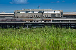 Wiese vom Tempelhofer Feld mit Blick auf die Rückseite des Flughafengebäudes mit dem Schriftzug Berlin-Tempelhof
