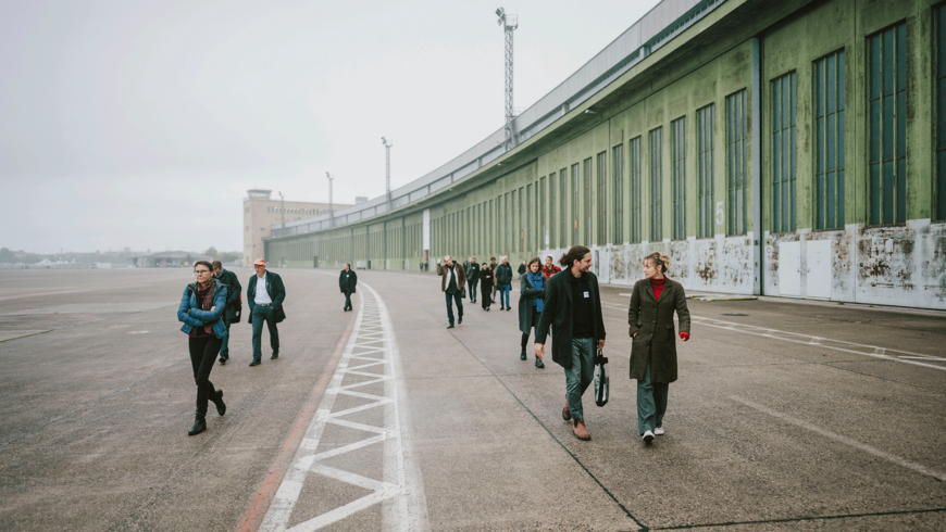 Menschen laufen bei Nebel über das weite Vorfeld des Flughafen Tempelhof