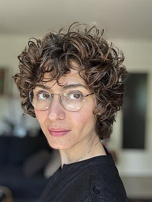 Porträt Foto von Zahra Mousawy, ihr Kopf ist zur linken Seite gedreht und sie schaut an der Kamera vorbei