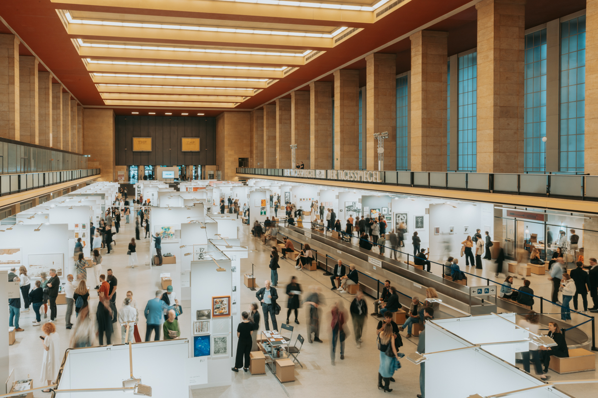 Viele Menschen in der Haupthalle des Flughafen Tempelhof, in der die Ausstellung Paper positions berlin stattfindet